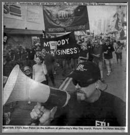 A black and white photo of a march. There is a banner saying "My Body My Business" in the background.